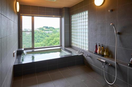 Nakanoスイートヴィラ オーシャンビュー南熱海的一间带大窗户和浴缸的浴室