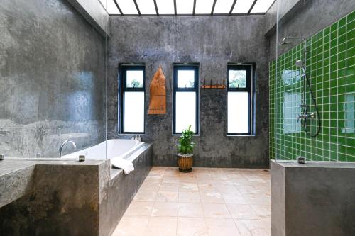 Na MueangCascade Tara的带浴缸、水槽和绿色瓷砖的浴室