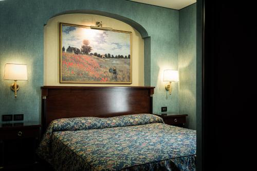 罗卡拉索小百合酒店的卧室配有一张床,墙上挂有绘画作品