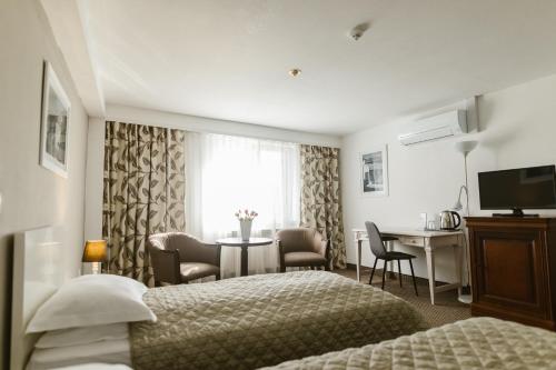 特尔古穆列什Villa Helvetia的酒店客房,设有两张床和一张桌子,椅子