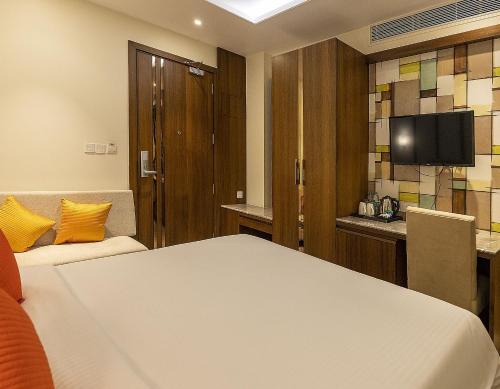 加尔各答Brio Hotel的一间酒店客房,配有一张床和一台电视