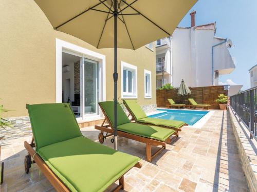 特罗吉尔Holiday Home Blue Dreams的一个带椅子和遮阳伞的庭院和一个游泳池