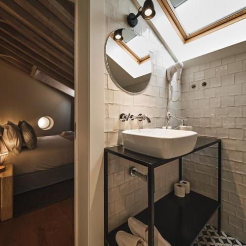 里斯本Look Living, Lisbon Design Apartments的一间带水槽和镜子的浴室以及一张床