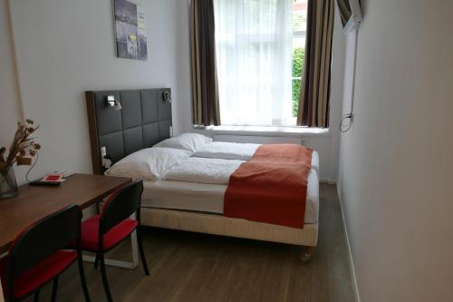 维也纳Comfy Mini Apartments Vienna的一间卧室配有一张床、一张书桌和一个窗户。