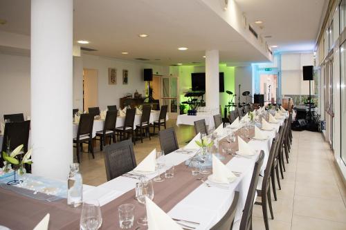 多博沃Hotel Kozana的一间长餐厅,配有白色的桌子和椅子