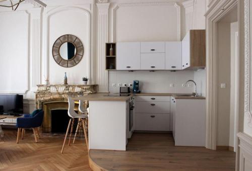 布雷斯地区布尔格Sublime appartement, chic et confortable.的厨房配有白色橱柜、桌子和壁炉。