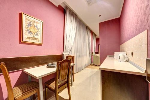 HatneTerra Nova Sport&Spa Hotel的一间设有粉红色墙壁和桌椅的房间