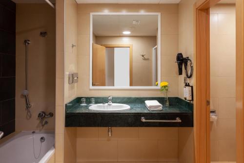 卡内拉岛Playamarina的浴室配有盥洗盆、镜子和浴缸