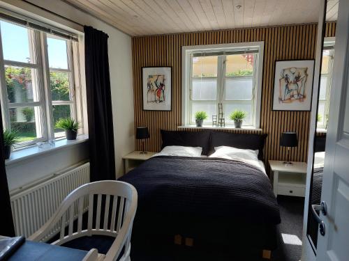 斯卡恩Toftegården Guesthouse - Apartments & Rooms的一间卧室设有一张床和两个窗户。