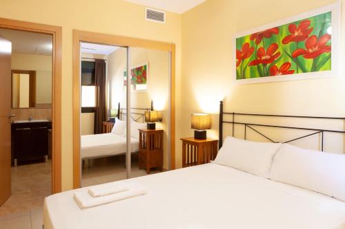 卡内拉岛Apartamentos Playamarina的卧室配有白色的床和镜子