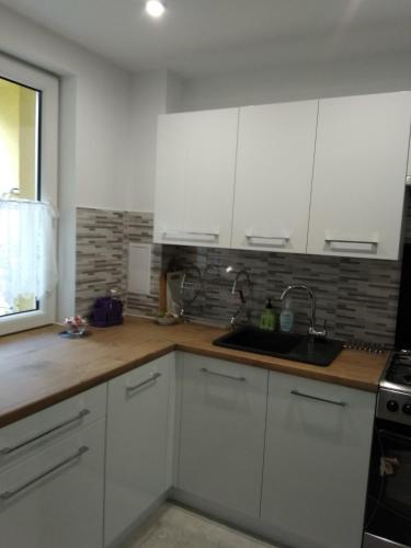 哈伊努夫卡Klimatyczne mieszkanie的厨房配有白色橱柜和水槽