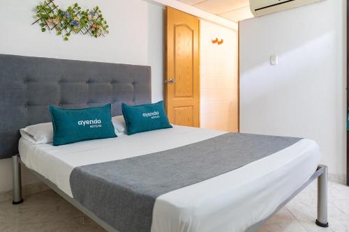 内瓦Hotel Ayenda Guadalupe的一间卧室配有一张带两个蓝色枕头的床