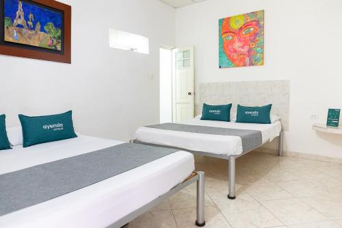 内瓦Hotel Ayenda Guadalupe的一间设有两张床的客房,墙上挂着一幅画