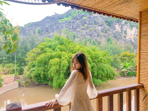 宁平Trang An Resort的站在一个眺望着河流的阳台的年轻女孩