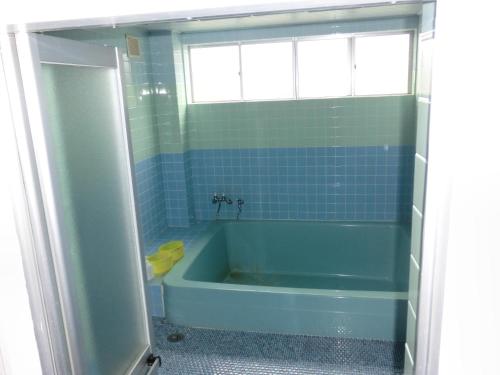 大津ペンションレークサイド的一间带蓝色浴缸和窗户的浴室