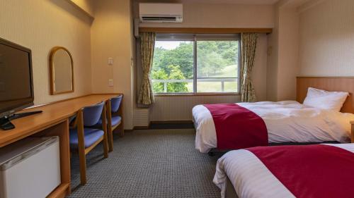 ShōbaraKyukamura Taishakukyo的酒店客房设有两张床、一张桌子和一台电视。