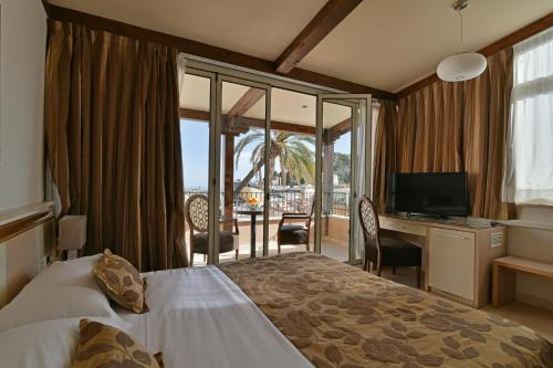 陶尔米纳Hotel Le Chevalier的酒店客房配有一张床和一张书桌及一台电视