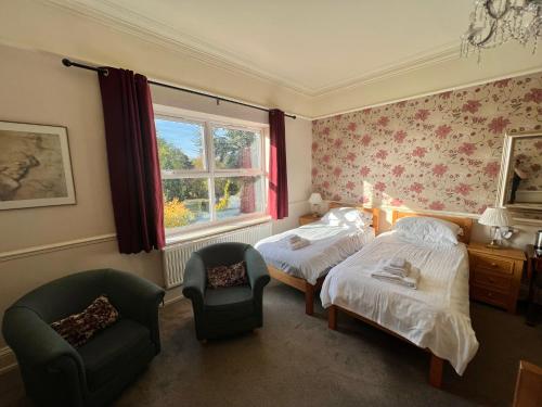 约克Melton Guest House的一间卧室设有两张床、一把椅子和一个窗户。