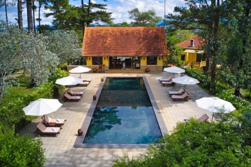 大叻Ana Mandara Villas Dalat Resort & Spa的享有带椅子和遮阳伞的游泳池的上方景色