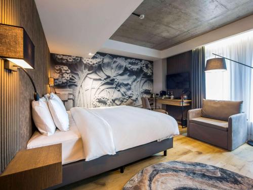 里加里加市中心美居酒店的一间卧室配有一张大床和一把椅子