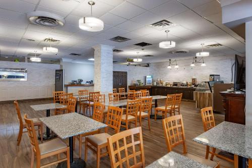 米西索加Quality Inn Toronto Airport的一间带木桌椅的餐厅和一间厨房