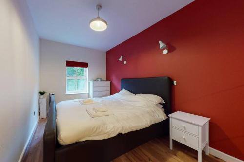 伦敦Lovely 2-bedroom flat with parking near Highgate的卧室设有一张红色的墙壁和一张床
