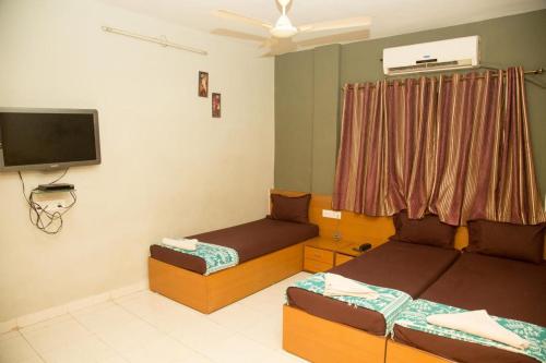 孟买Srujan Sarai Service Apartment的客房设有两张床和一台平面电视。