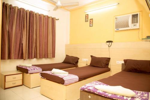 孟买Srujan Sarai Service Apartment的客房设有两张床和窗户。