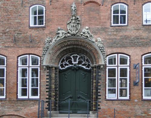 吕贝克安诺1216酒店的砖楼一侧的绿门