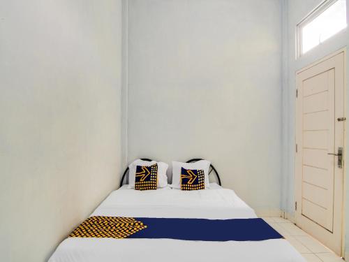ParitSPOT ON 91834 Sg 99 Homestay Syariah的白色卧室配有蓝色和黄色枕头的床