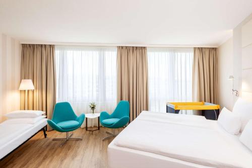 柏林NH酒店柏灵亚历山大广场店的酒店客房带两张床和一张桌子以及椅子。