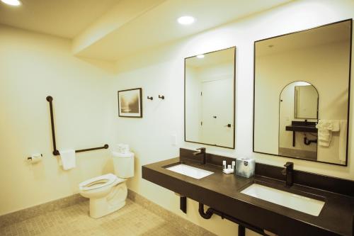 麦克默里堡Baymont by Wyndham Fort McMurray的浴室设有2个水槽、卫生间和镜子。