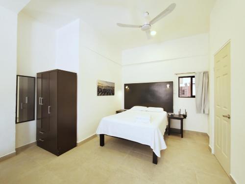 科苏梅尔Quinta Suites的卧室配有白色的床和黑色橱柜。