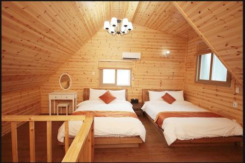西归浦市Zain Village的小木屋内一间卧室,配有两张床