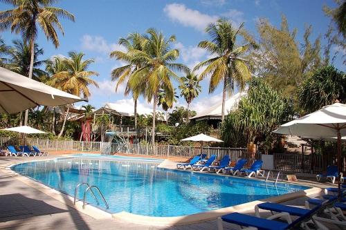 莱特鲁瓦西莱Res MARINA-CARAYOU 1的一个带椅子和遮阳伞的游泳池以及棕榈树