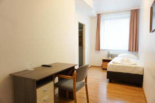 维也纳Hotel Kaffeemühle的一间卧室配有书桌和一张带窗户的床