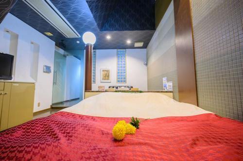 香芝市BLAN VILLA 旧bibi的一间设有一张红色毯子和黄色鲜花的床的房间