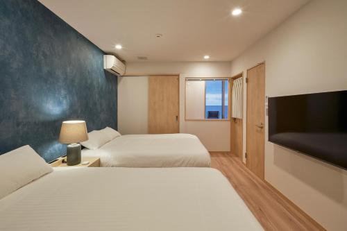 ItoshimaALFACIO RESORT STAY ITOSHIMA的酒店客房设有两张床和一台平面电视。