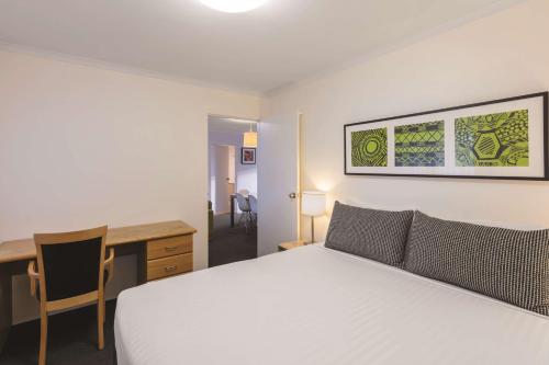 堪培拉堪培拉金斯顿阿迪纳服务公寓式酒店的卧室配有白色的床、书桌和书桌。