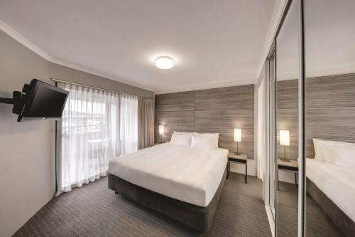 堪培拉堪培拉詹姆斯阁阿迪纳服务式公寓式酒店的酒店客房,配有床和电视