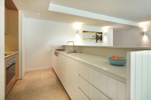 悉尼悉尼邦迪海滩阿迪娜公寓式酒店的厨房配有白色橱柜和柜台上的蓝色碗