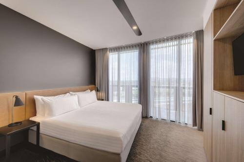 堪培拉堪培拉盛传酒店 的卧室设有白色的床和大窗户