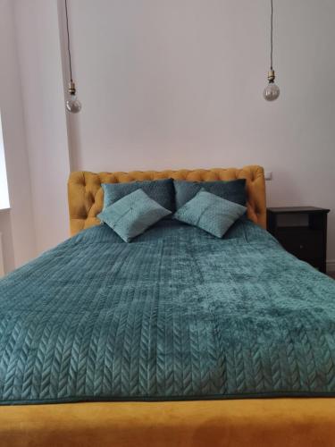 波兹南Apartament w kamienicy的一张带绿色棉被和蓝色枕头的床