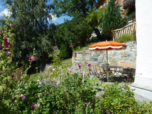 阿尔宾内Ferienhaus Turilji的花园设有桌子、雨伞和鲜花