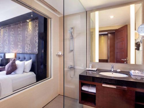 梭罗Grand Mercure Solo Baru的浴室配有盥洗盆和带镜子的淋浴