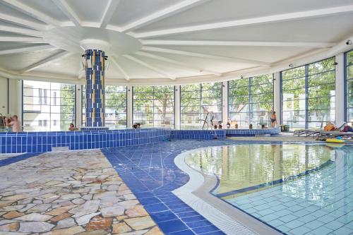 伦达瓦Thermal Resort Hotel Lendava的大型游泳池设有蓝色瓷砖地板和窗户。