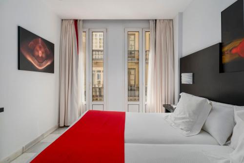 马拉加画家酒店的卧室设有红色和白色的床和窗户。