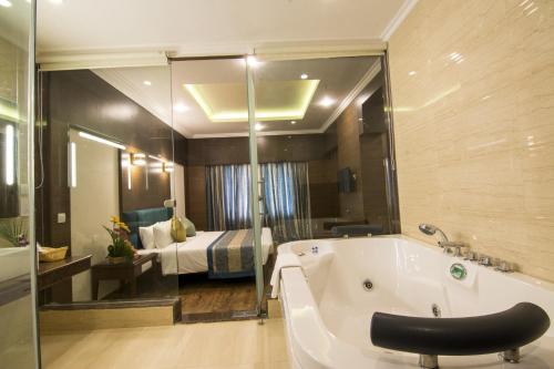 蓬蒂切里舍巴格会议中心酒店的带浴缸的浴室和1间带1张床的卧室
