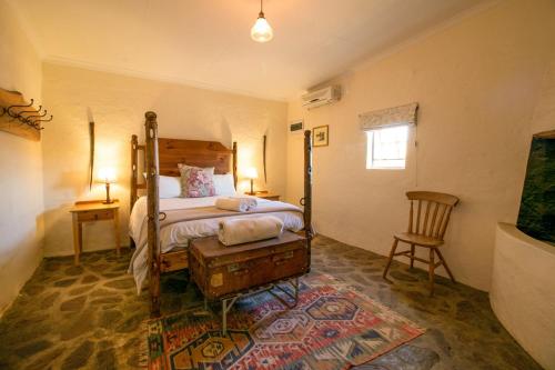格拉夫-里内特Wild Olive Cottage的卧室配有1张床、1张桌子和1把椅子