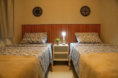 帕尔马斯Casa Pequena, Completa e Aconchegante - Tiny House的酒店客房设有两张床和床头柜。